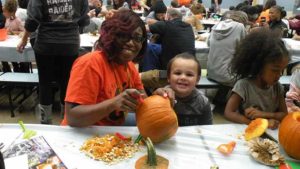 Ms. Marshall helps a student carve his pumpkin.