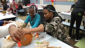 A student and her middle school helper clean out their pumpkin.