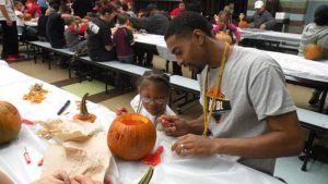 A student and her helper decide on a face for their pumpkin.