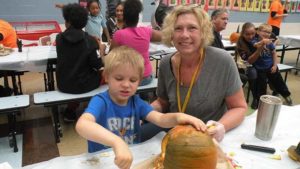 A student and his helper clean out their pumpkin.