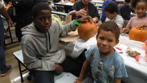 A student and his helper get ready to clean out their pumpkin.