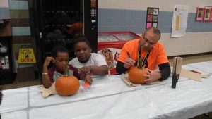 Mr. Israel and two students working on their pumpkins.