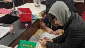 An Eighth grader listens as a Second grader explains his work.