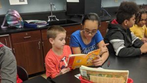An Eighth grader student listens to a Second grader read his book.