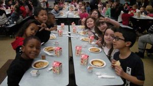 A class smiles as they start eating their pancakes.