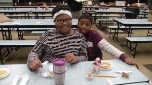 Two fifth grade girls pause for a picture while enjoying their pancakes.