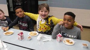 Second grade boys smile for a picture before their pancakes.