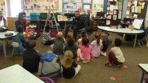 A class listens as their guest shares a story with them.