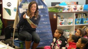 A guest reader smiles as she reads a funny part to the story.