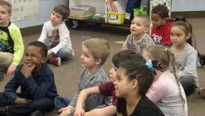 Students smile as they listen to a story.