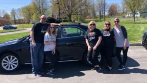 The third grade teachers stand in front of a car and pose for a picture.