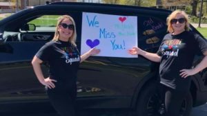 Third grade teachers pointing to their poster "We Miss You".