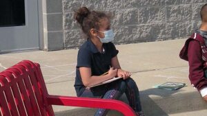 A student listens to her teacher as she prepares to take notes.