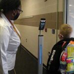 A student gets his temp taken before going to class.