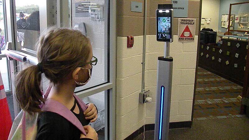 A student gets her temp checked before going to class in the morning.