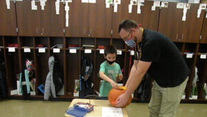 Mr. Bitner holds the pumpkin so a student can collect seeds