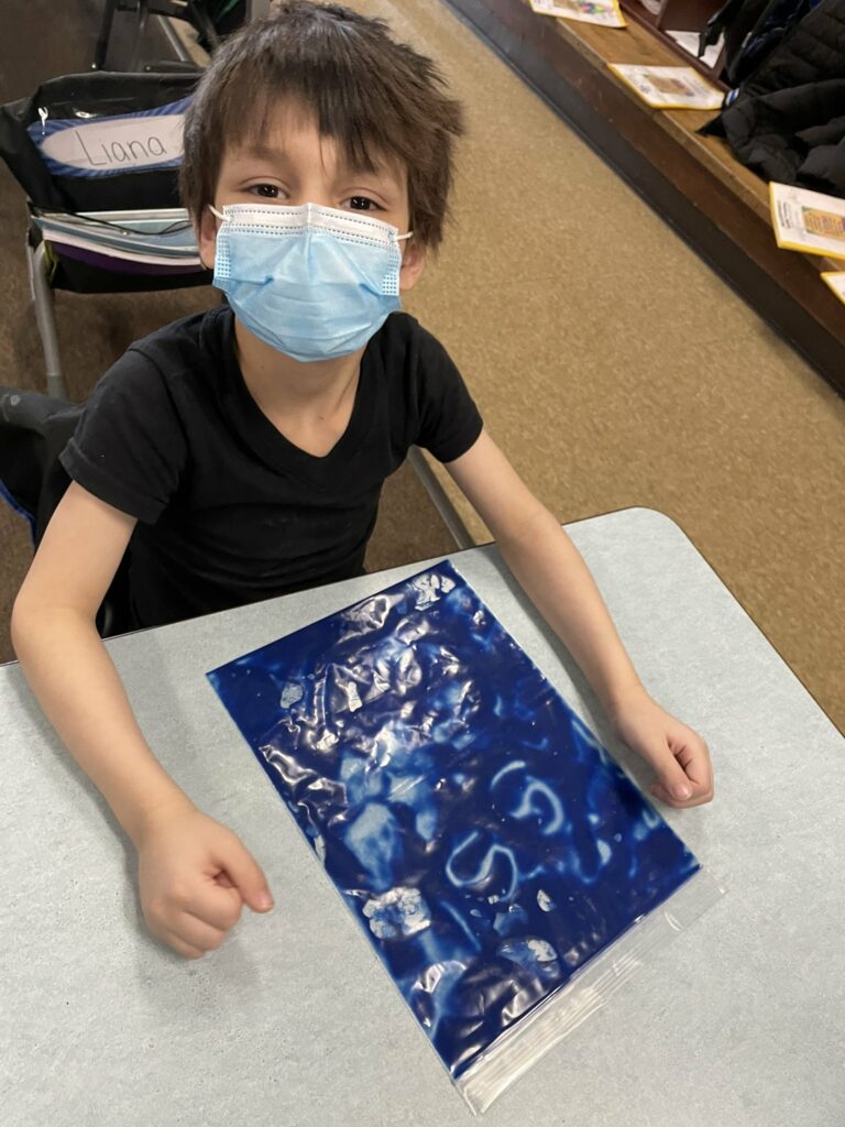 Practicing his letter 'S' using his paint bag.