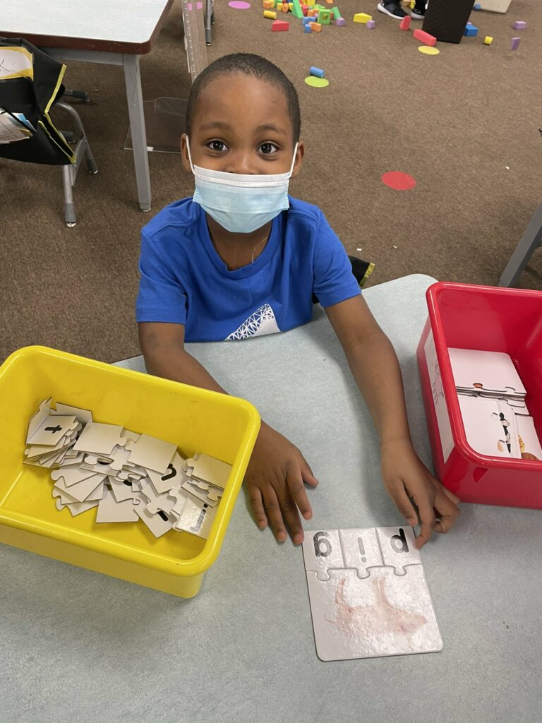 A kindergarten student practicing words through the use of letter sound pieces.