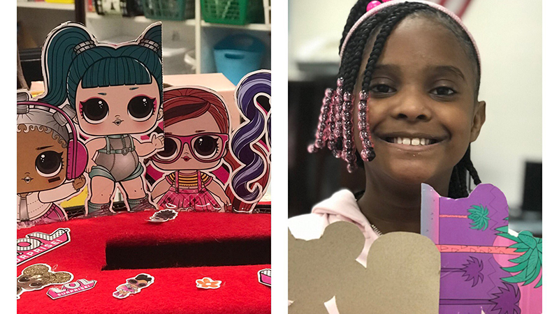 A student smiles as she shows her valentine box.