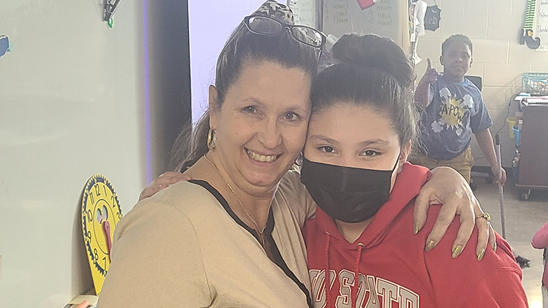 Student stands next to her former fourth grade teacher.