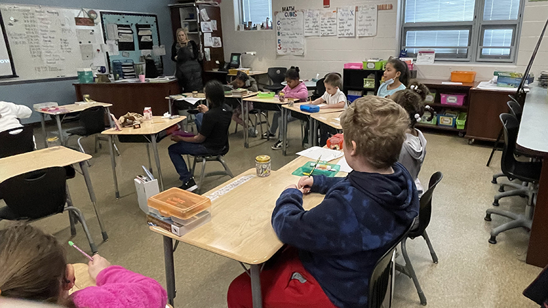 third grade students listen to instructions as they begin their math problem of the day.