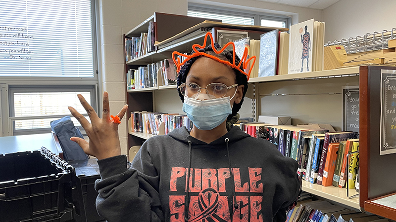 A student shows off her pipe cleaner jewelry.