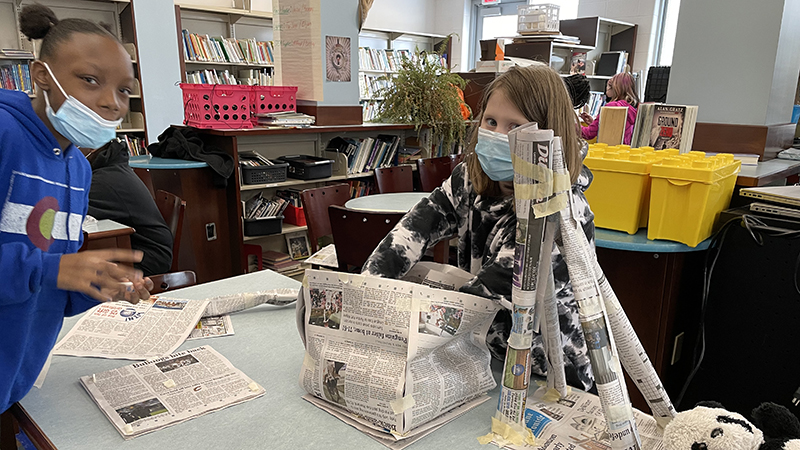 Students building a tower using newspaper.
