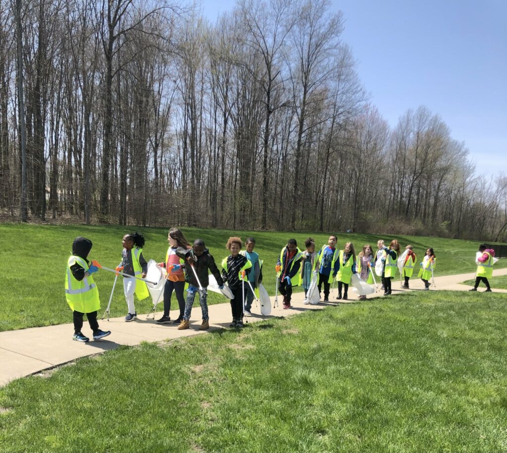 students walk in a line outside ready to clean up for earth day.