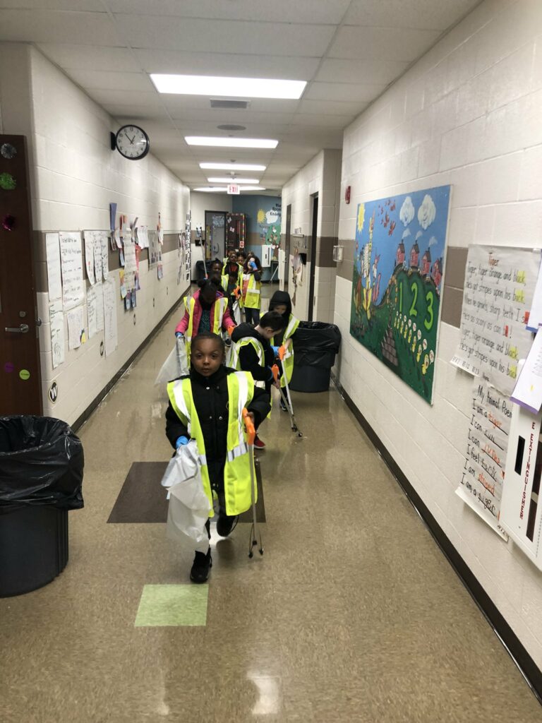 students walk in a line down the hall wearing their earth day gear