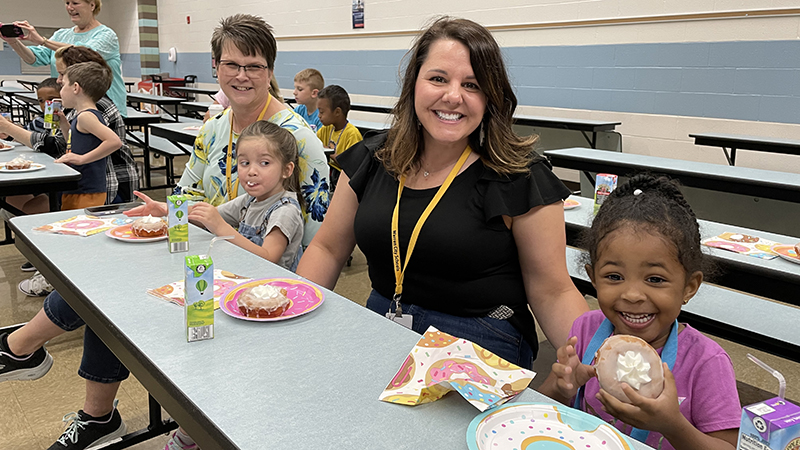 Preschoolers enjoy their donut award with Mrs. Logan.