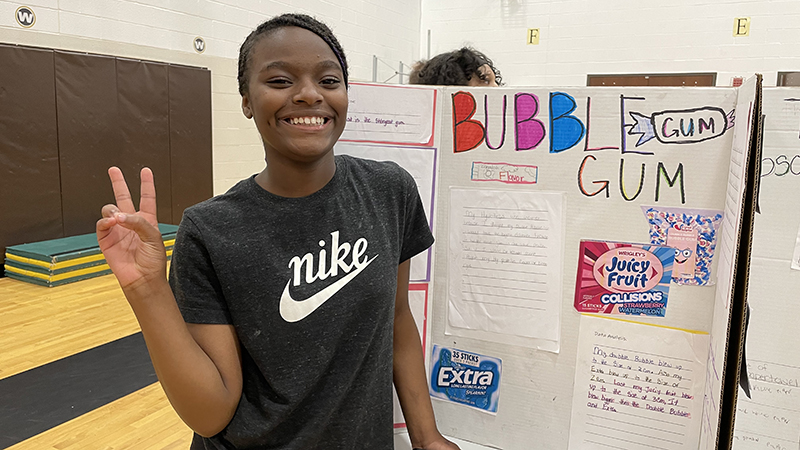 A student with their project about bubble gum.
