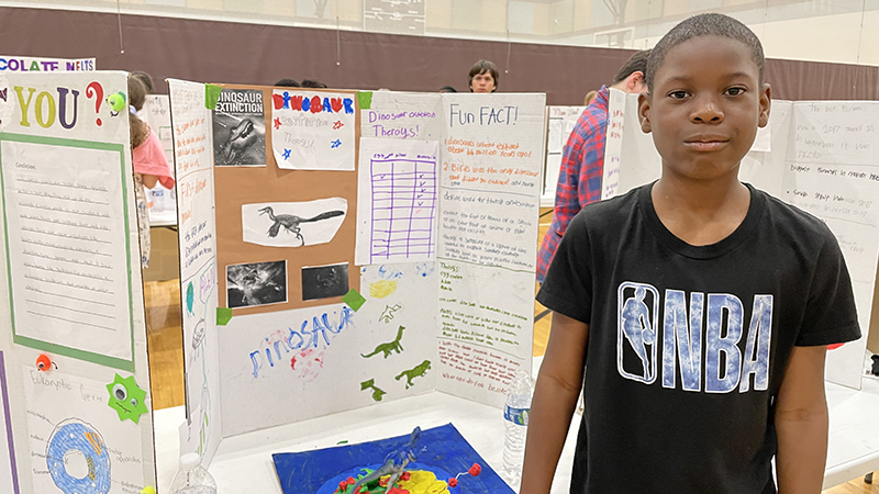 A sixth grader shows his project about dinosaurs.