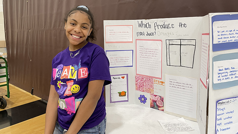 A student shows her science project about oranges.