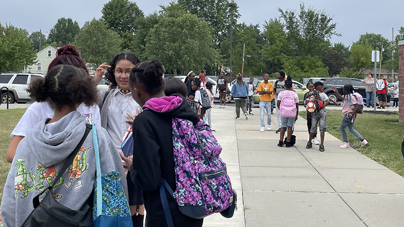 students standing together as they wait or the school day to start.