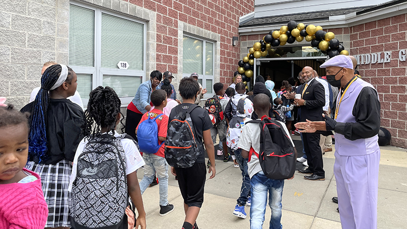 students entering the building as they ae greeted by community members.
