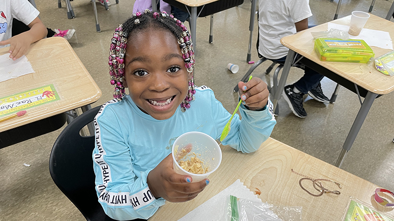 A student smiles as she eats her apple pie.