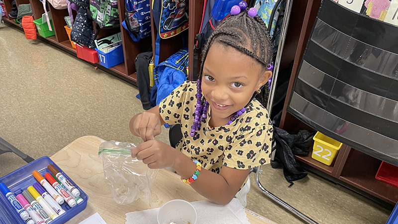 A student adds more topping to her apple pie treat.