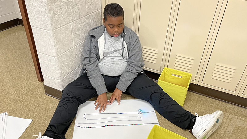 Student watches his robot follow the path he created.