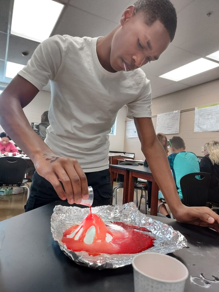A student pours liquid on his volcano.