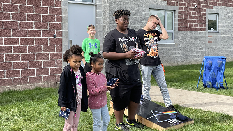 Eighth graders teach younger students how to play corn hole.
