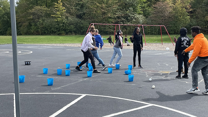 Students playing a bucket toss game together.