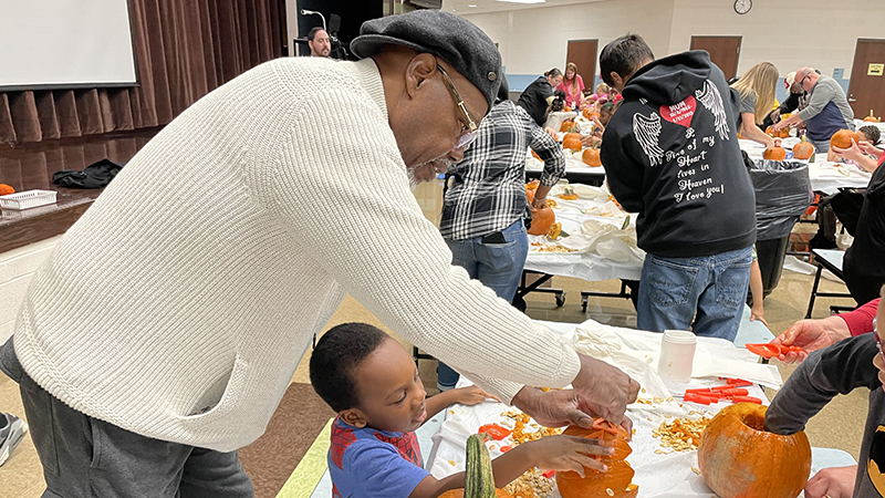 A helper carving out a student's pumpkin.