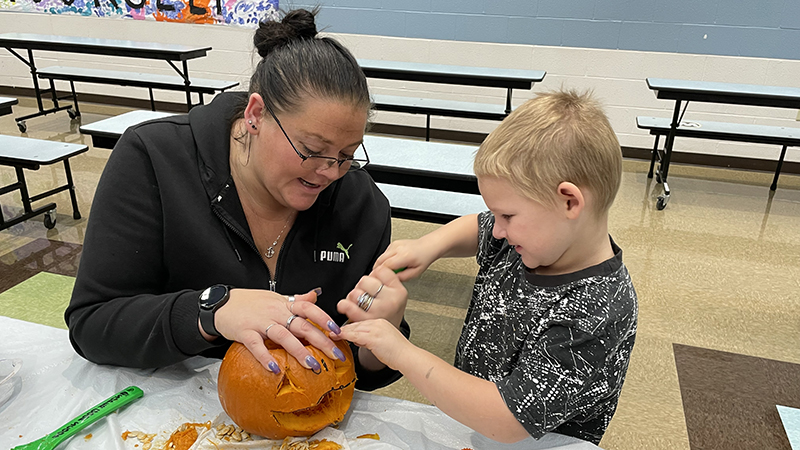 A student helps to carve his pumpkin.