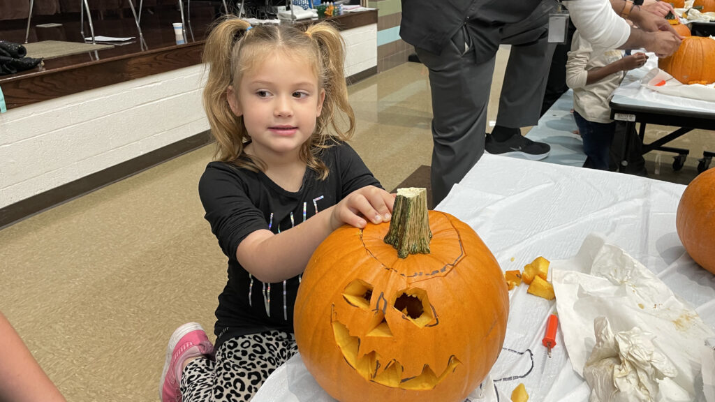 A student shows off her finished pumpkin.
