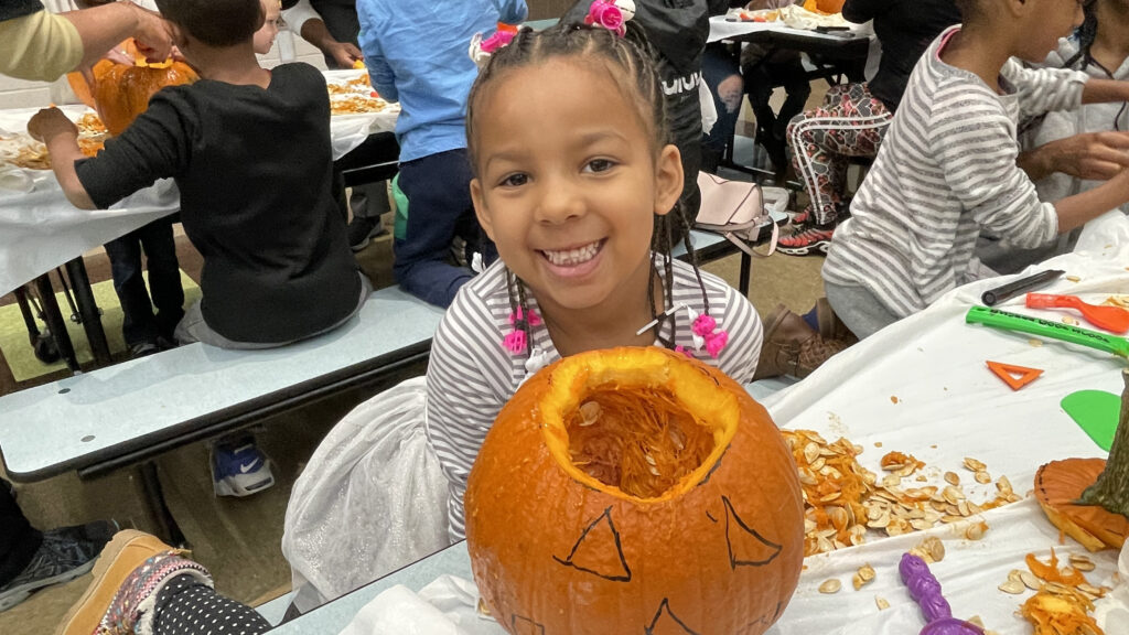 A student shows off the face she drew for her pumpkin.