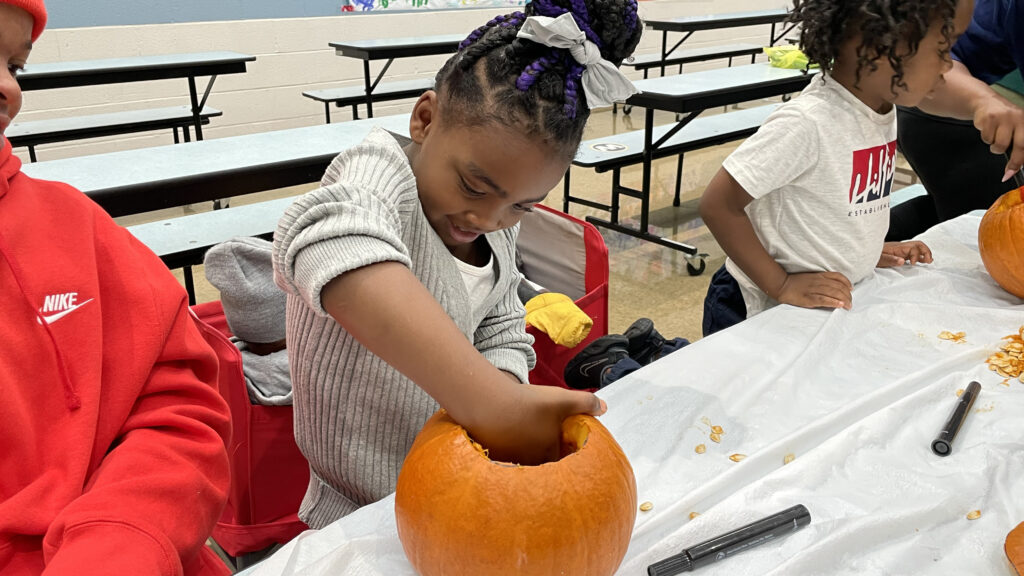 A student cleaning out her pumpkin.