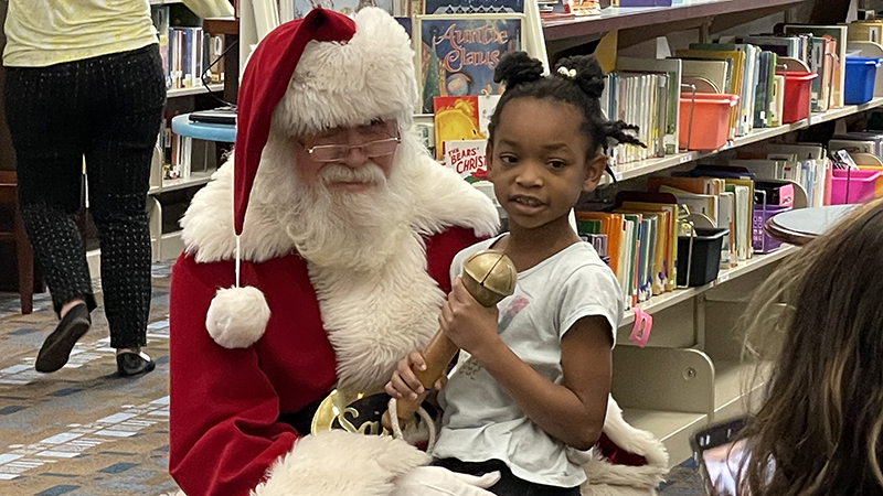 A student gets to hold Santa's bell.
