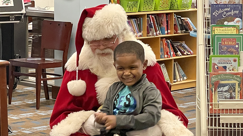 a student smiles for a picture with Santa.