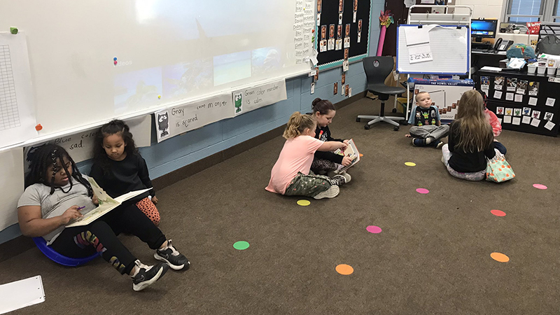 students sit together on the carpet reading books.