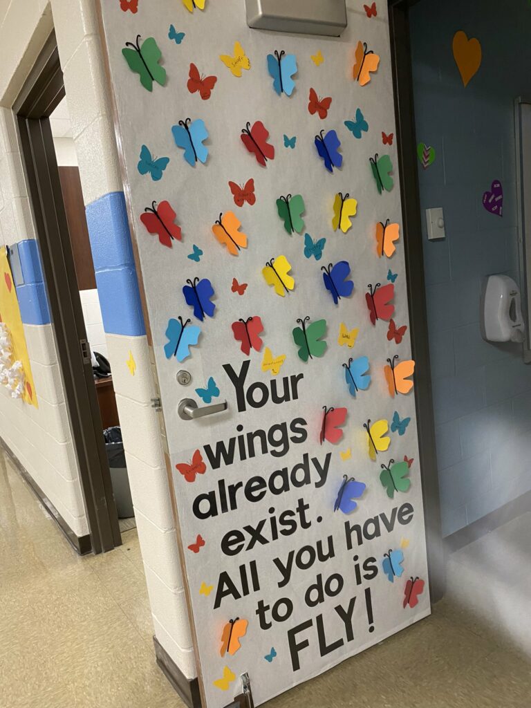 A door decorated with butterflies and the phrase "Your wings already exist. All you have to do is fly."